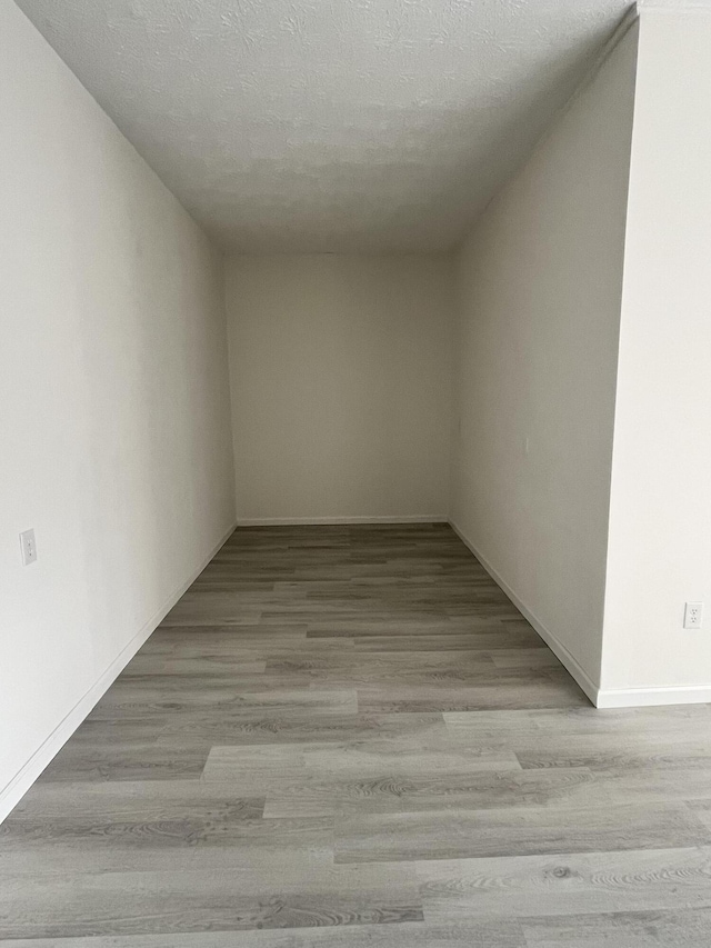 empty room with light hardwood / wood-style floors and a textured ceiling