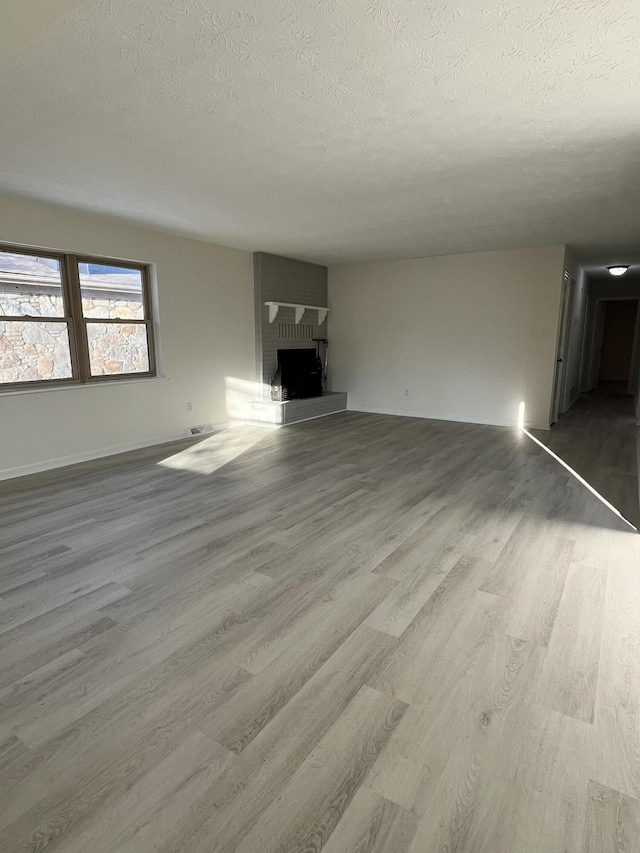 unfurnished living room featuring a textured ceiling, a fireplace, and light hardwood / wood-style flooring