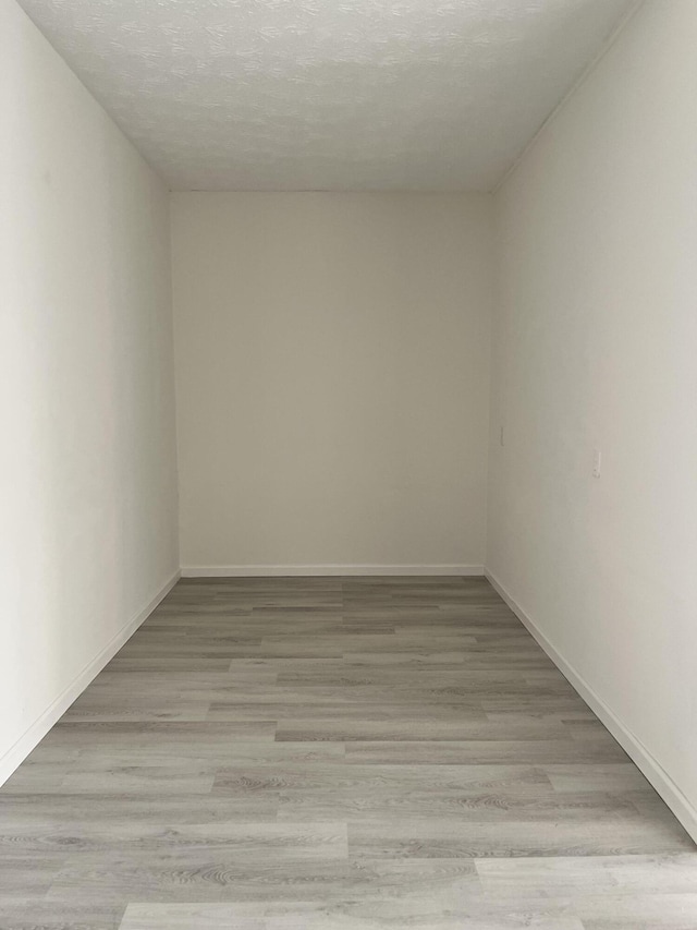 unfurnished room with light hardwood / wood-style flooring and a textured ceiling