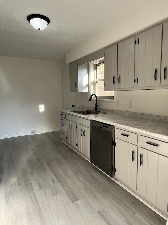 kitchen featuring white cabinetry, dishwasher, sink, and light wood-type flooring