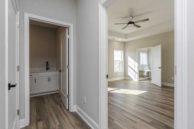 bedroom featuring baseboards, a tray ceiling, visible vents, and wood finished floors