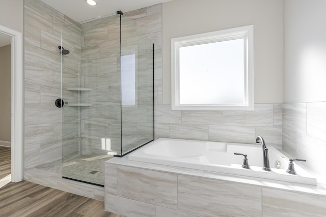 bathroom with a stall shower, wood finished floors, and a bath