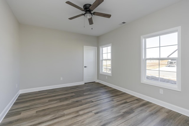 spare room featuring ceiling fan, dark wood finished floors, and baseboards