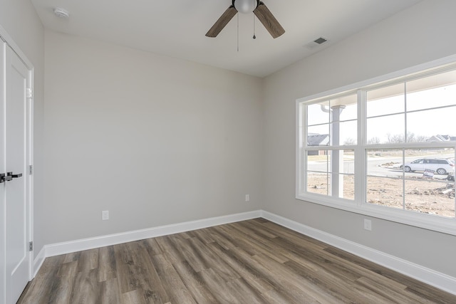 spare room with ceiling fan, dark wood-style flooring, visible vents, and baseboards