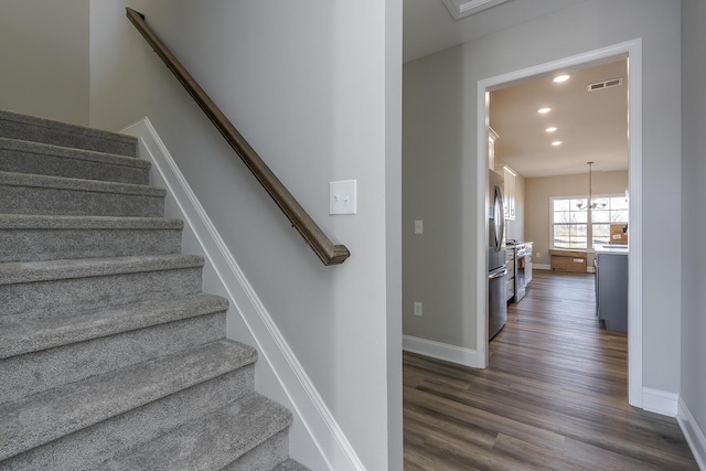 stairway featuring baseboards, wood finished floors, visible vents, and recessed lighting