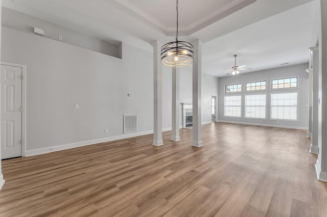 unfurnished living room featuring ceiling fan, a raised ceiling, light hardwood / wood-style flooring, and ornate columns