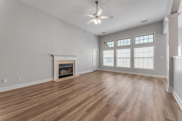 unfurnished living room with ceiling fan, wood-type flooring, and a tile fireplace