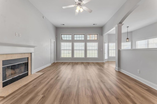 unfurnished living room with decorative columns, wood-type flooring, ceiling fan, and a fireplace