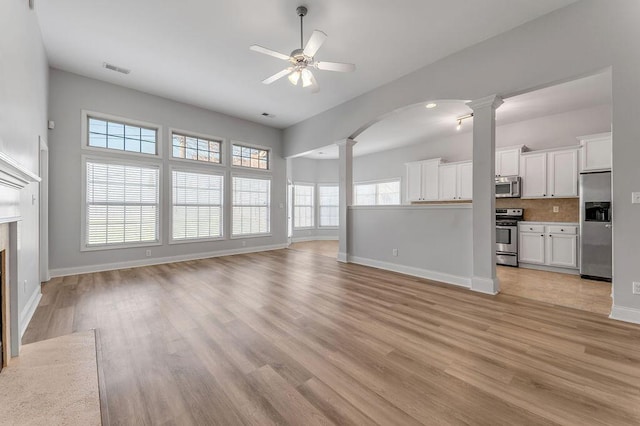 unfurnished living room featuring light hardwood / wood-style flooring, ceiling fan, and ornate columns