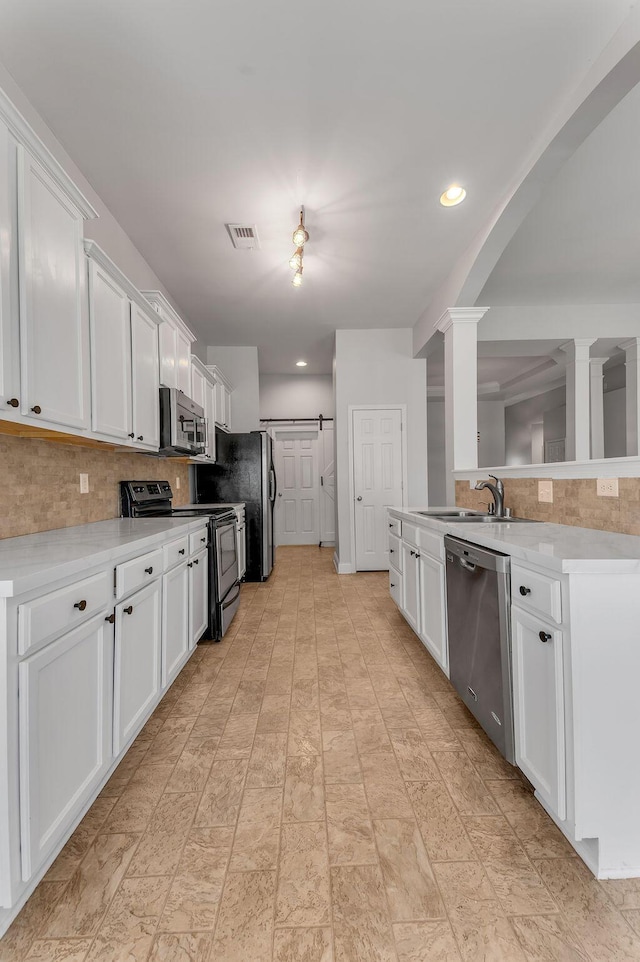 kitchen with backsplash, stainless steel appliances, decorative columns, and white cabinets