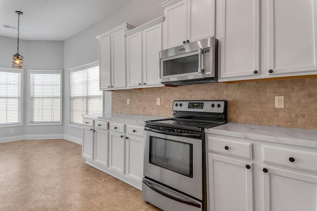 kitchen featuring decorative light fixtures, tasteful backsplash, white cabinetry, stainless steel appliances, and light stone countertops