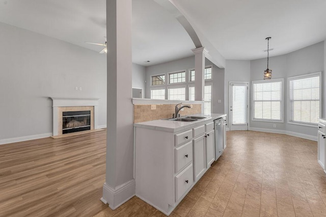 kitchen featuring sink, white cabinetry, decorative light fixtures, dishwasher, and a tiled fireplace