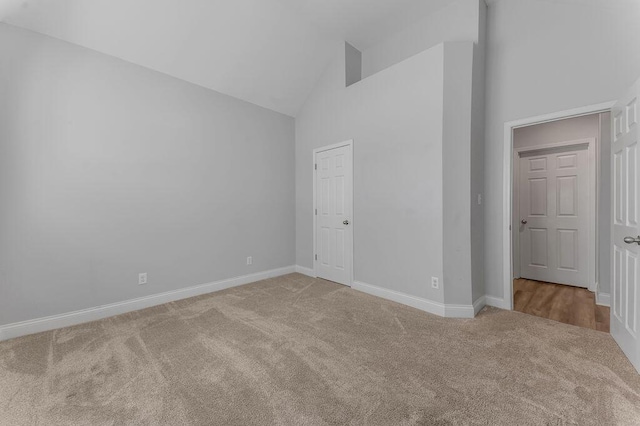 unfurnished bedroom with carpet floors and high vaulted ceiling