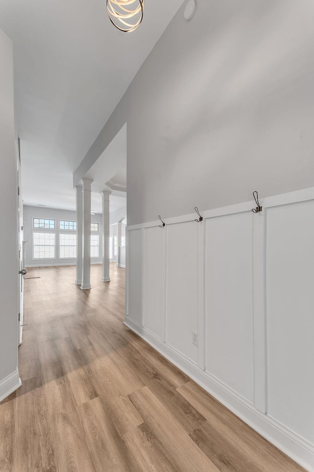 corridor featuring decorative columns and light wood-type flooring