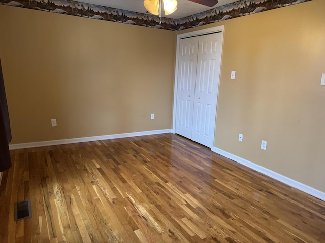 unfurnished bedroom with hardwood / wood-style flooring, ceiling fan, and a closet