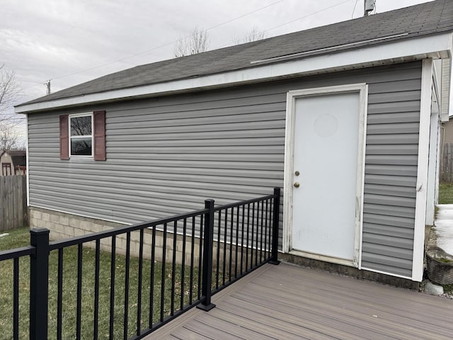 view of exterior entry featuring a deck and a lawn