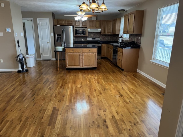 kitchen with decorative light fixtures, wood-type flooring, sink, backsplash, and black appliances