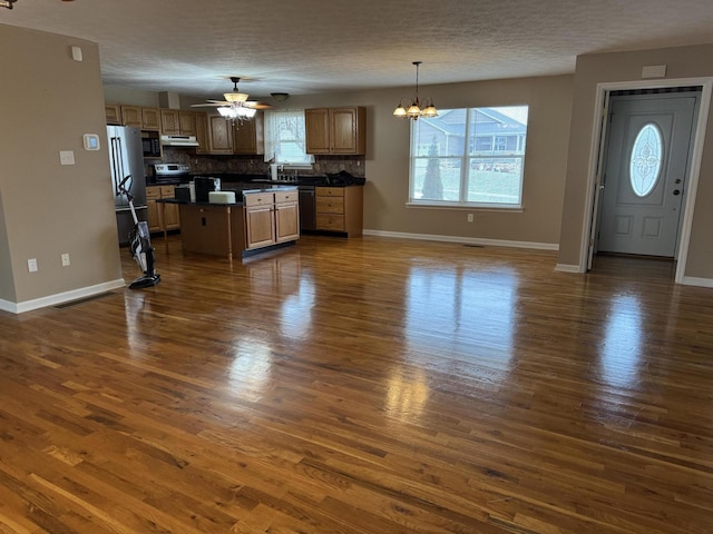 kitchen featuring a center island, appliances with stainless steel finishes, dark hardwood / wood-style floors, pendant lighting, and backsplash