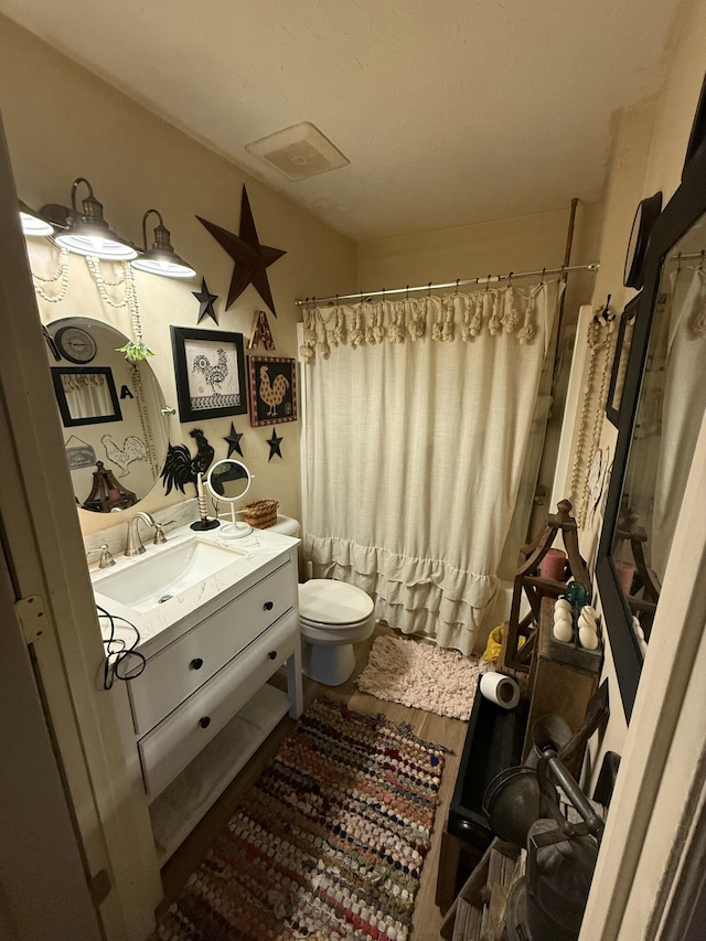 bathroom featuring walk in shower, vanity, toilet, and wood-type flooring