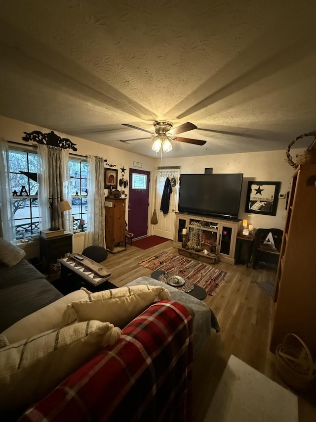 living room with ceiling fan, wood-type flooring, and a textured ceiling