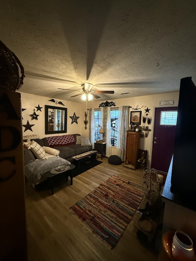 living room with ceiling fan, wood-type flooring, a textured ceiling, and plenty of natural light