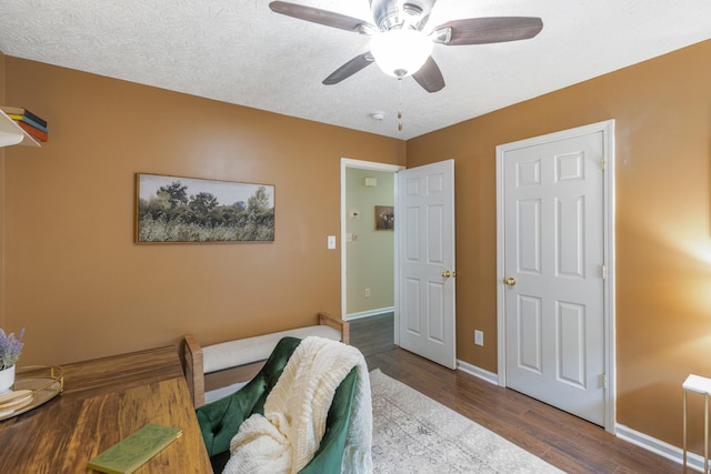 bedroom with a textured ceiling, wood-type flooring, and ceiling fan