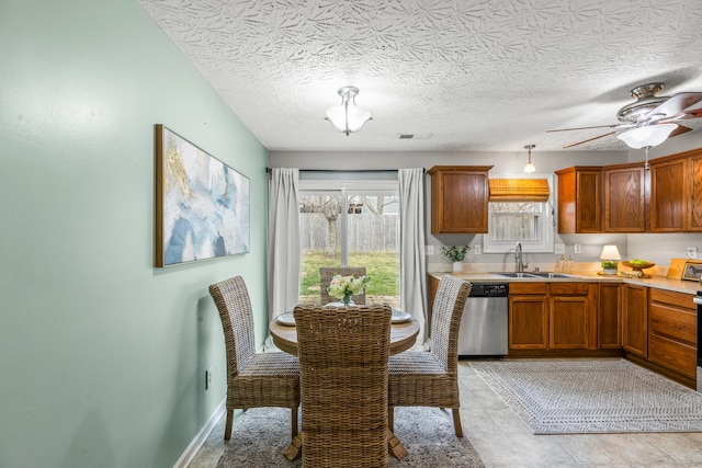 kitchen with ceiling fan, sink, stainless steel dishwasher, and a textured ceiling