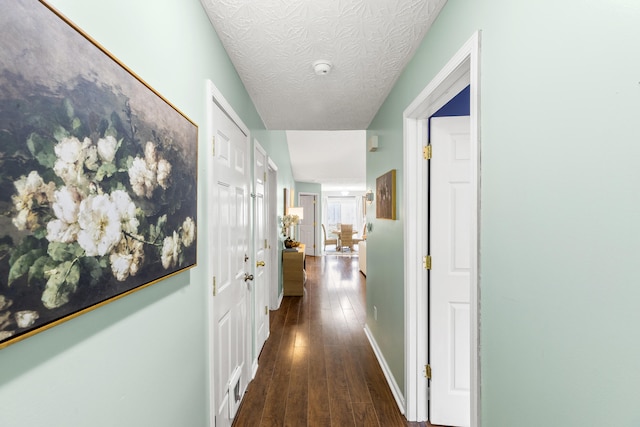 hallway with dark hardwood / wood-style flooring and a textured ceiling