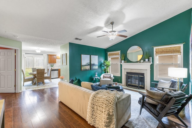 living room featuring vaulted ceiling, ceiling fan, a textured ceiling, and dark hardwood / wood-style flooring