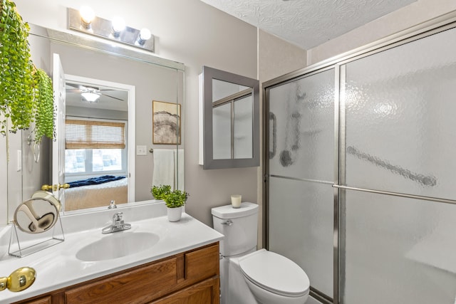 bathroom featuring vanity, a textured ceiling, a shower with shower door, and toilet