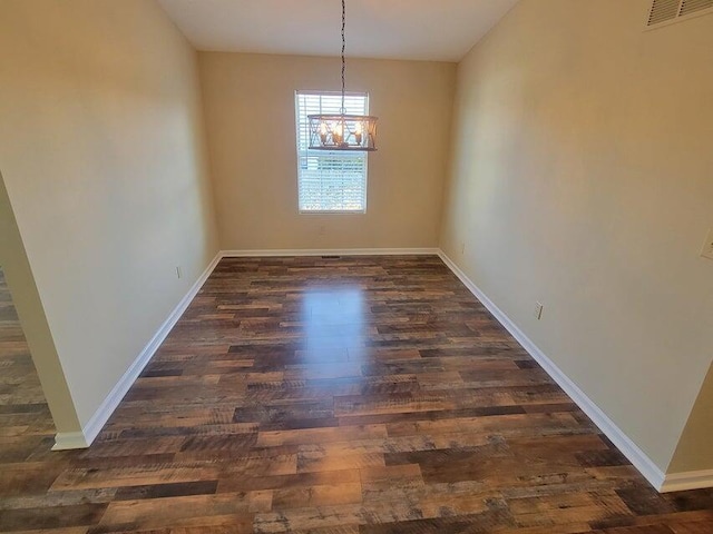 unfurnished dining area featuring an inviting chandelier and dark hardwood / wood-style flooring