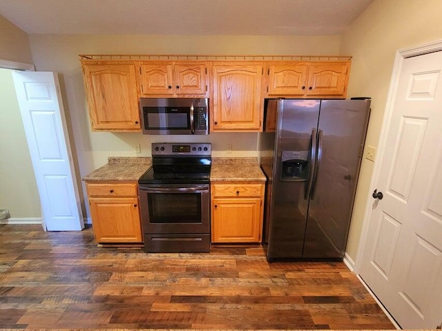 kitchen with appliances with stainless steel finishes, dark hardwood / wood-style floors, light brown cabinets, and light stone counters