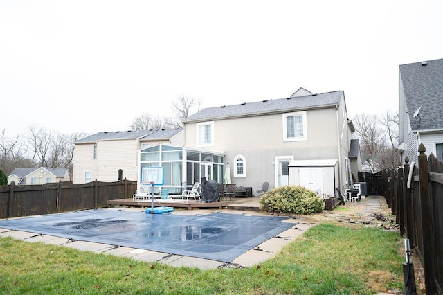 rear view of house featuring a wooden deck, a sunroom, a yard, and a patio area