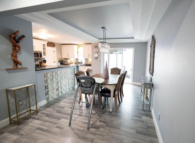 dining space with a tray ceiling, dark hardwood / wood-style flooring, and a notable chandelier