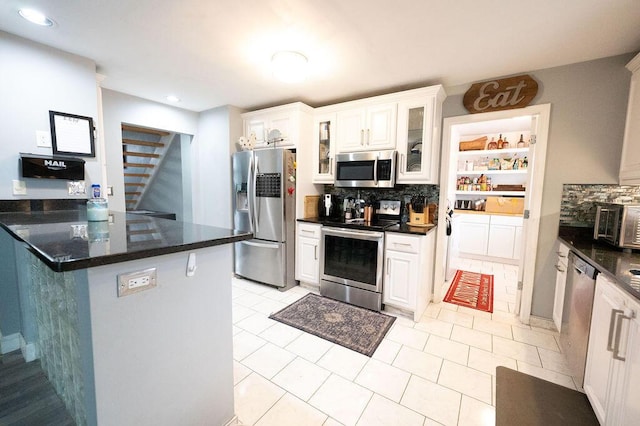 kitchen with white cabinetry, appliances with stainless steel finishes, tasteful backsplash, and light tile patterned floors