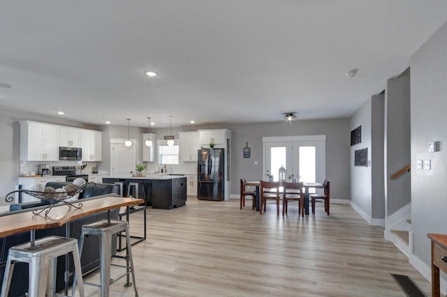 dining area with recessed lighting, light wood-style flooring, baseboards, and stairs