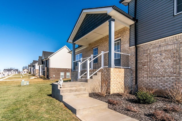 property entrance with brick siding, a lawn, and a residential view