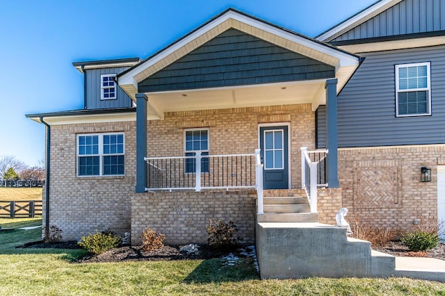 view of front facade with board and batten siding, brick siding, fence, and a porch