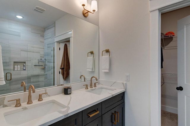 bathroom with a spacious closet, a sink, a shower stall, and double vanity