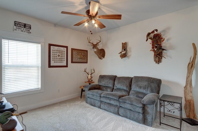 carpeted living area with ceiling fan and baseboards