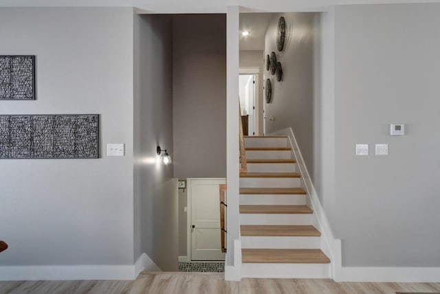 staircase featuring wood finished floors and baseboards