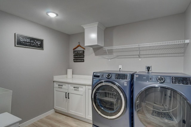 laundry area featuring cabinet space, light wood-style flooring, baseboards, and separate washer and dryer