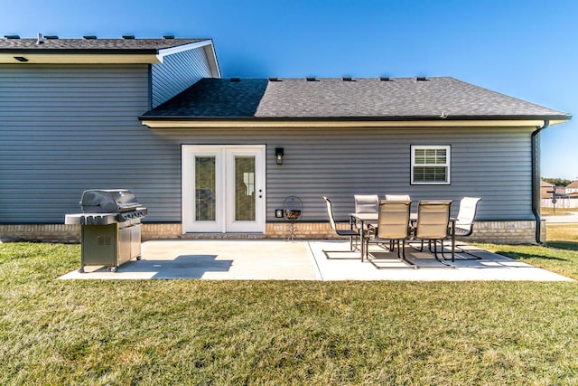 back of property with a patio, a shingled roof, and a lawn