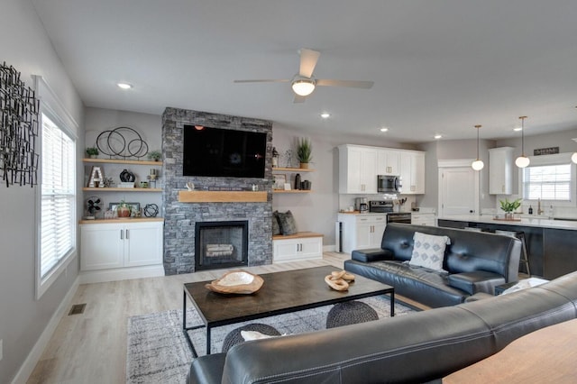 living area with light wood-style flooring, a fireplace, visible vents, and recessed lighting