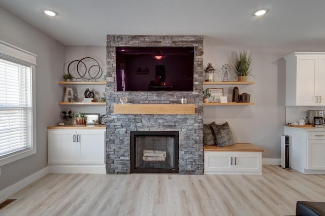 unfurnished living room featuring light wood-style floors, visible vents, a fireplace, and baseboards