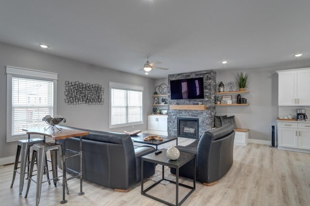 living room featuring light wood finished floors, a fireplace, and baseboards