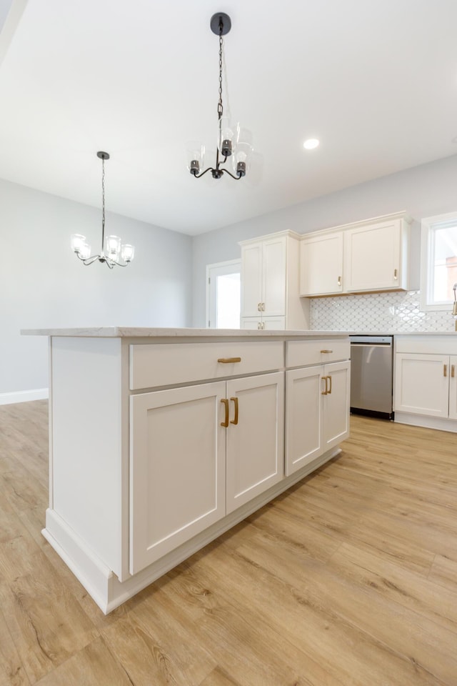 kitchen featuring pendant lighting, dishwasher, white cabinetry, a notable chandelier, and decorative backsplash