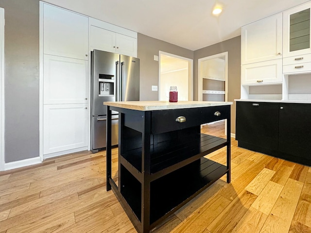 kitchen with white cabinets, light hardwood / wood-style flooring, high quality fridge, and a kitchen island