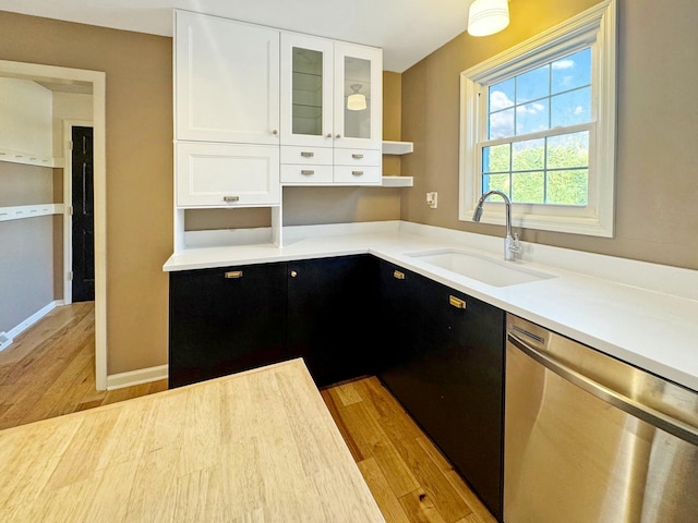 kitchen featuring sink, stainless steel dishwasher, white cabinets, and light wood-type flooring