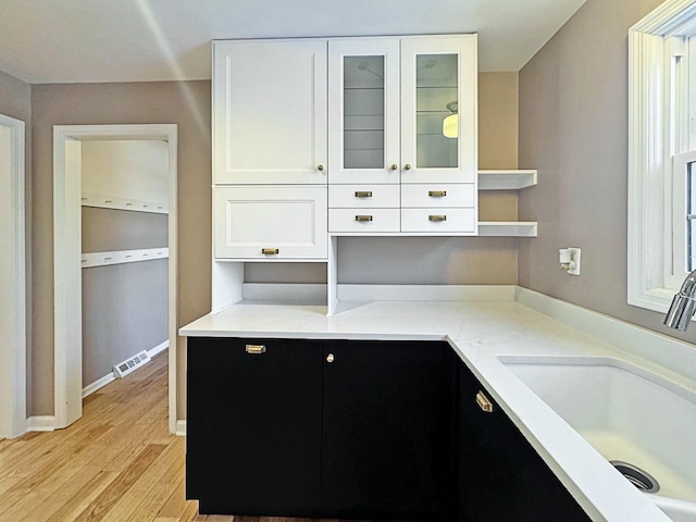 kitchen with white cabinets, light hardwood / wood-style flooring, and sink